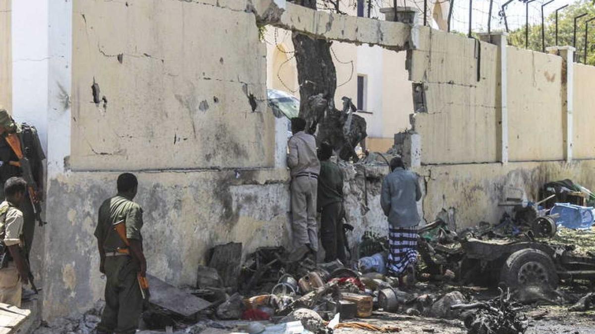 Miembros de las Fuerzas de Seguridad somalíes se asoman al interior junto al muro de un edificio gubernamental atacado por yihadistas en Mogdiscio