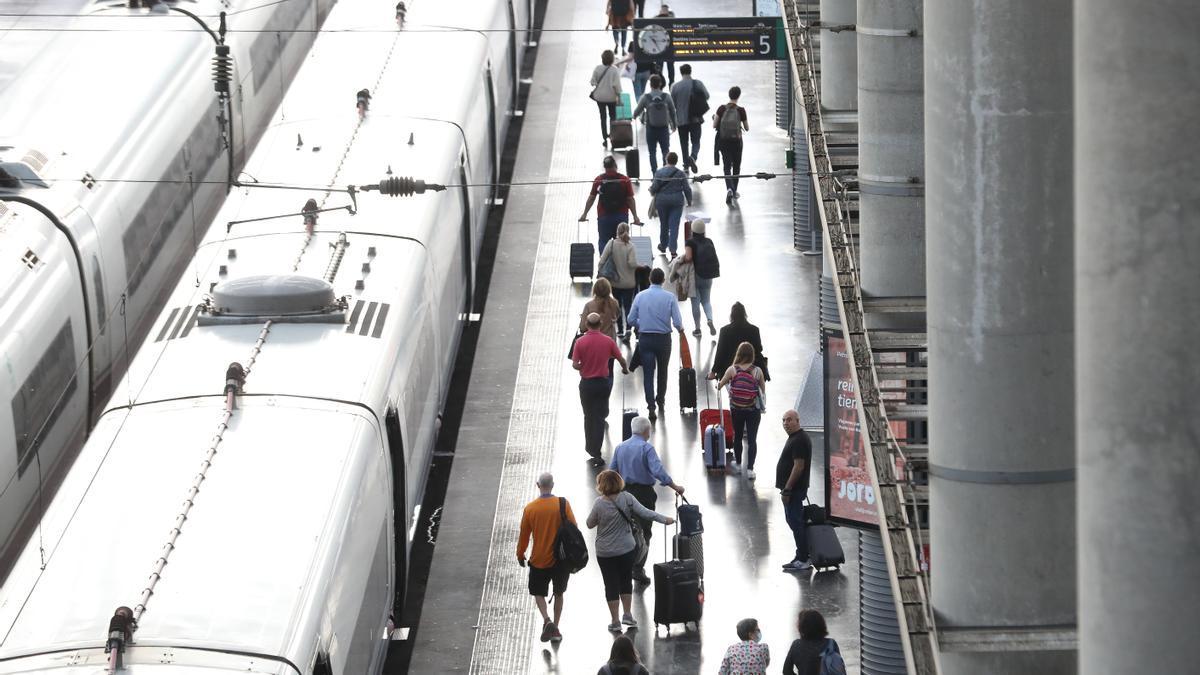 Varios pasajeros con maletas en el andén de un tren en la estación de Puerta de Atocha.