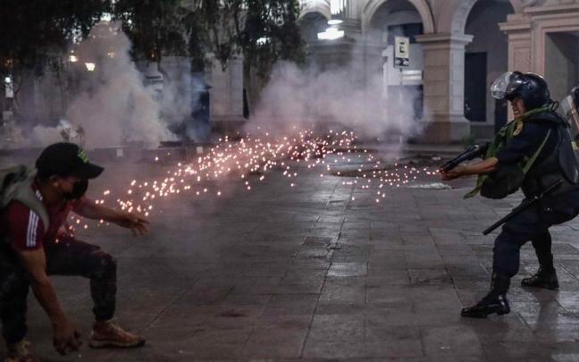 Un manifestante y un policía se enfrentan en las protestas en Lima.