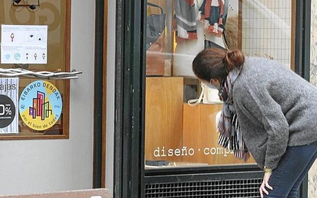 Una mujer limpia el escaparate de una tienda de Eibar. | FOTO: J.L.