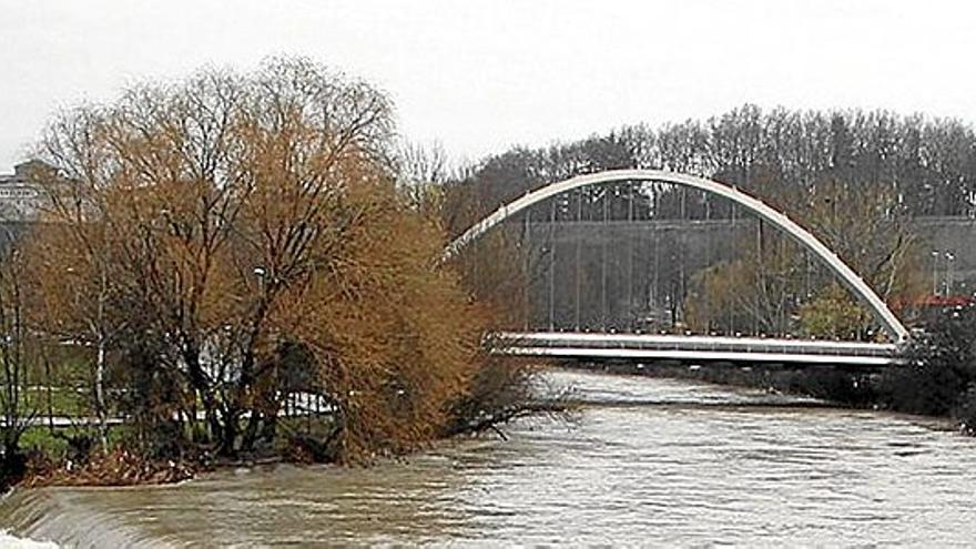 El puente de Oblatas, al fondo, durante una crecida del Arga. | FOTO: JAVIER BERGASA