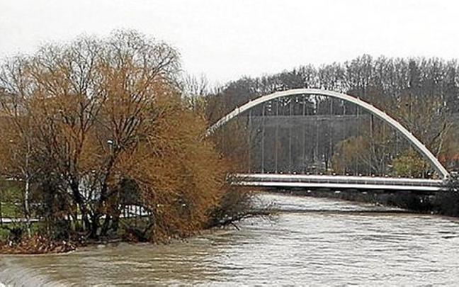 El puente de Oblatas, al fondo, durante una crecida del Arga. | FOTO: JAVIER BERGASA