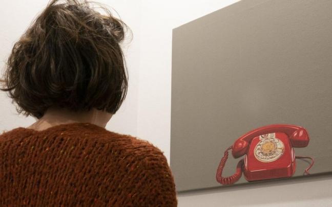 Una joven observa el tel&eacute;fono impreso en un lienzo, en la sede donostiarra del Tel&eacute;fono de la Esperanza de Gipuzkoa.