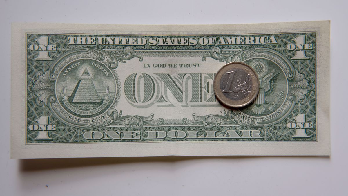 Una moneda de euro sobre un billete de dólar.