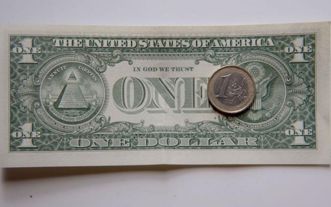 Una moneda de euro sobre un billete de dólar. Una moneda de euro sobre un billete de dólar.