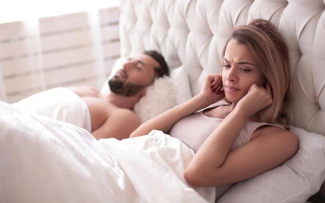 Una mujer se tapa los oídos mientras su marido duerme. Una mujer se tapa los oídos mientras su marido duerme.