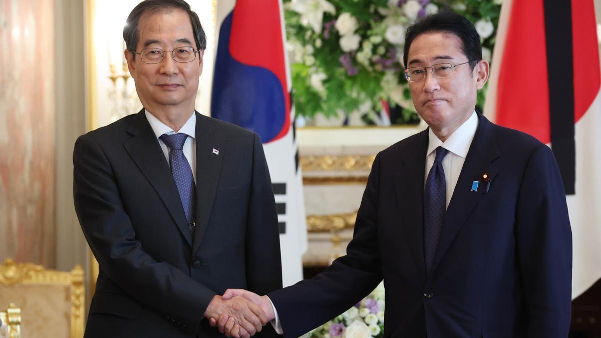 El primer ministro surcoreano Han Duck-soo (izq.) estrecha la mano del primer ministro japonés Fumio Kishida (der.).