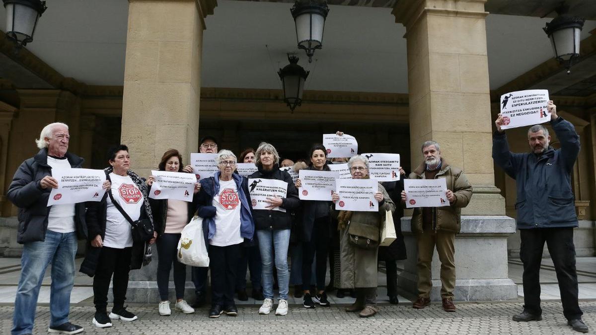 Los vecinos y vecinas del barrio donostiarra de Gros afectados por el Fondo de Inversión Azora, este mediodía, en la entrada del Ayuntamiento de Donostia.