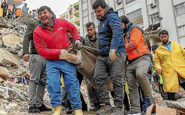 Un hombre lanza un grito desgarrador mientras acarrea un cuerpo sin vida sacado de los escombros en Adana. Foto Can EROK/Afp