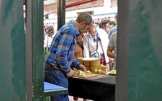 Un comerciante de queso, a mediodía, mientras atendía a varios clientes que hacían cola para degustar. | FOTO: MAIDER GOIKOETXEA Un comerciante de queso, a mediodía, mientras atendía a varios clientes que hacían cola para degustar. | FOTO: MAIDER GOIKOETXEA