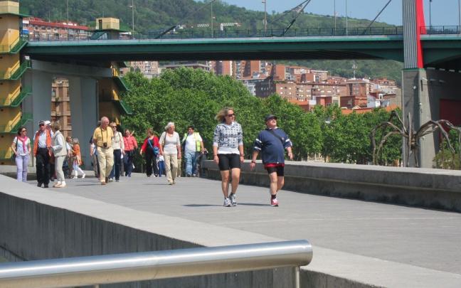 Varios turistas pasean junto a la r&iacute;a de Bilbao.