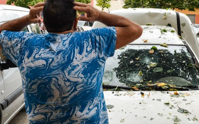 Un hombre con las manos en la cabeza al ver el estado de la luna de su vehículo, como consecuencia de la tormenta de granizo en la Bisbal d’Empordà.