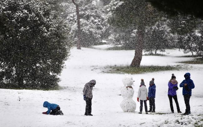 Unos niños hacen un muñeco de nieve tras una nevada.