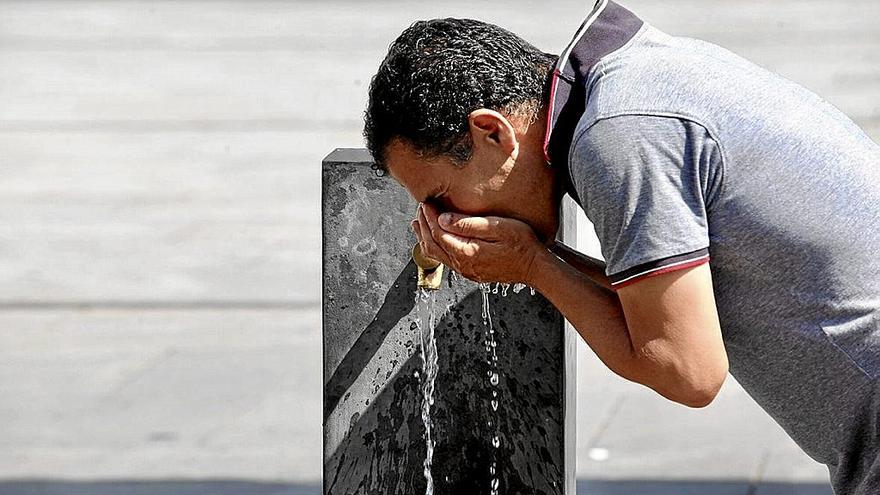 Un hombre bebe agua de una fuente de Vitoria.