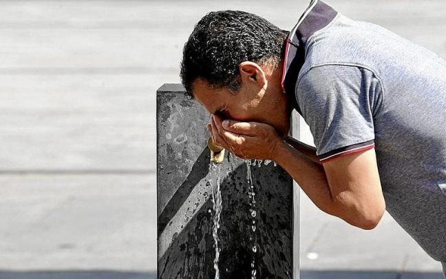 Un hombre bebe agua de una fuente de Vitoria.