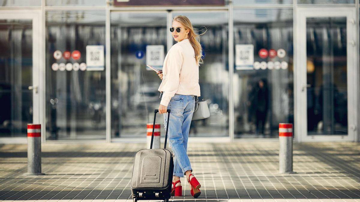 Una mujer llega al aeropuerto arrastrando su maleta.