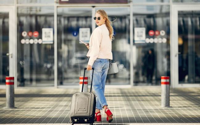 Una mujer llega al aeropuerto arrastrando su maleta.