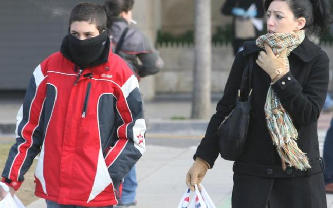 Dos personas abrigadas con guantes y bufanda para protegerse del frío en Pamplona, en una imagen de archivo.