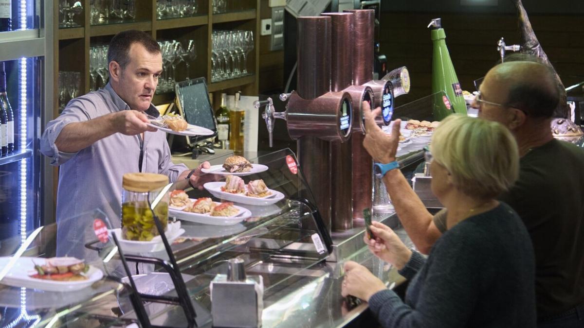 Julián sirve varios pintxos a sus clientes, este miércoles en el Bodegón Sarría.