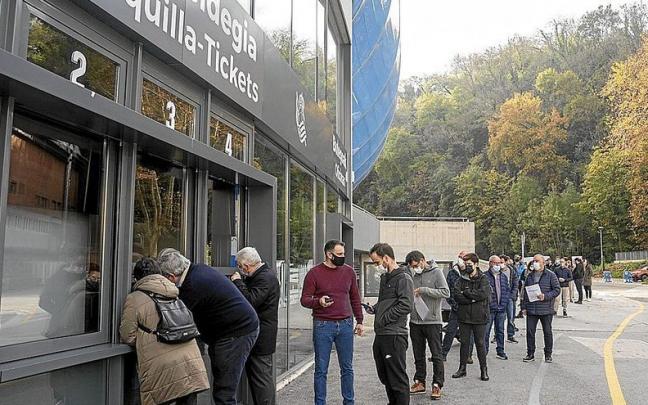 Varias personas hacen cola frente a la taquilla del estadio de Anoeta.