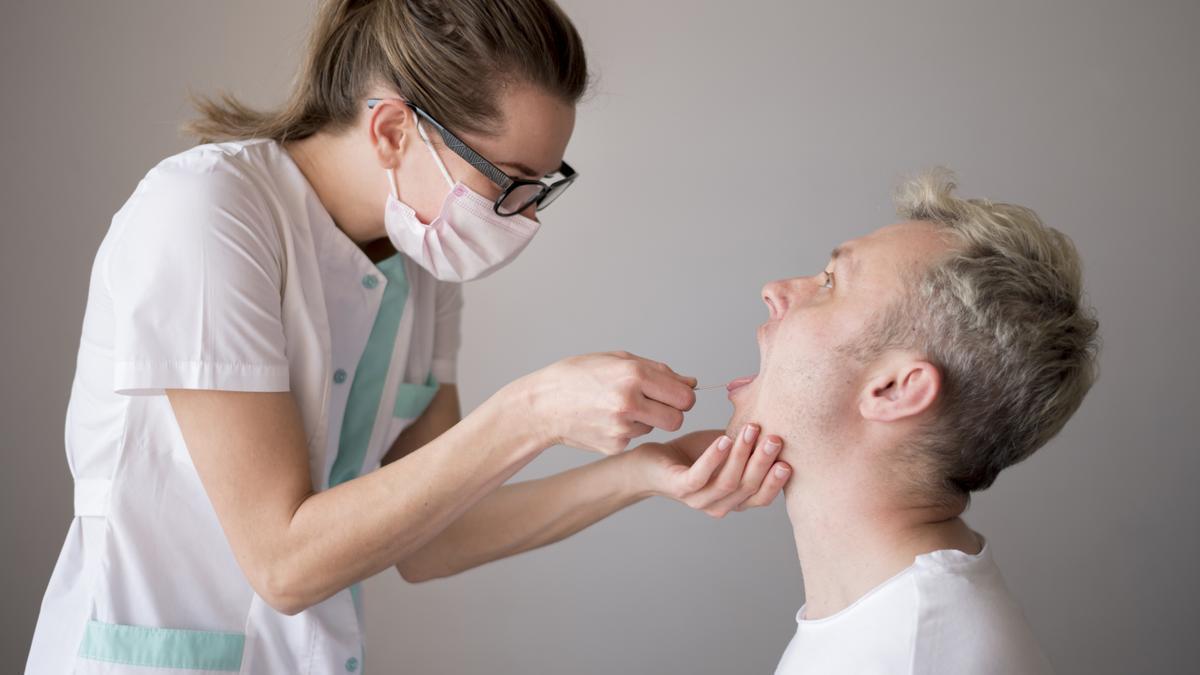 Una médico examina la boca de un paciente