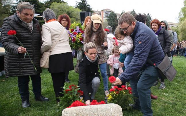 Varias personas depositan flores en la Vuelta del Castillo.
