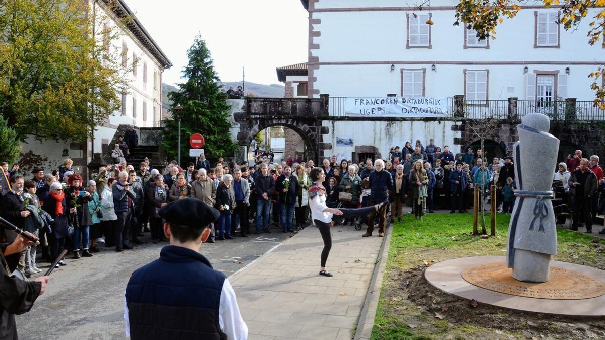 Oihana Santxotena, de Baztandarra dantza taldea, bailando el aurresku, delante de la escultura de Mikel Iriarte, y rodeada de la gente que asistió al homenaje.