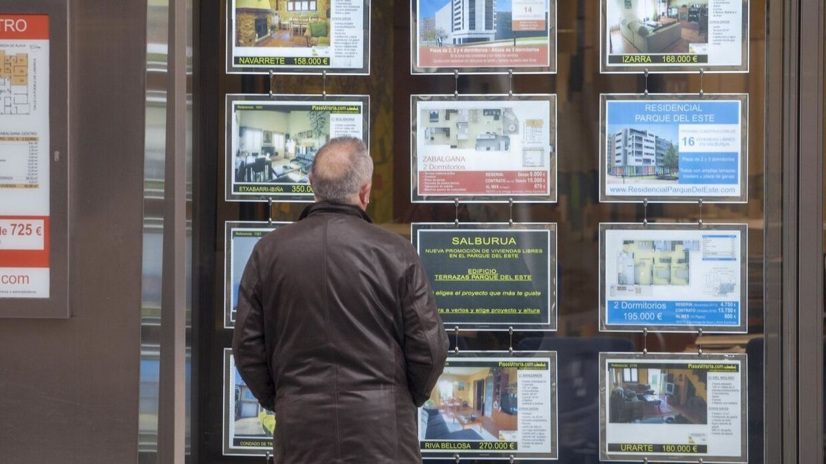 Un hombre mirando un escaparate con las ofertas de pisos en venta y alquiler de una inmobiliaria