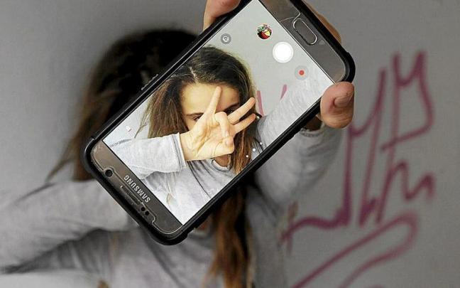 Una niña se hace un selfi con su teléfono móvil mientras los expertos piden que se racione la cantidad y los momentos del uso del mismo. | FOTO: OSKAR M. BERNAL Una niña se hace un selfi con su teléfono móvil mientras los expertos piden que se racione la cantidad y los momentos del uso del mismo. | FOTO: OSKAR M. BERNAL