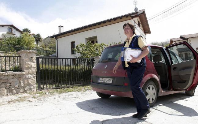 Una cartera rural sale de su coche para repartir la correspondencia en Eusa