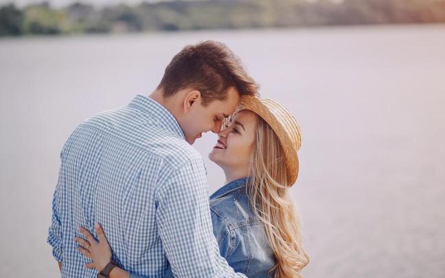 Una joven pareja en actitud cari&ntilde;osa frente al mar.