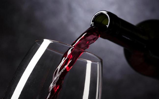 Vino tinto vertido de una botella a una copa.