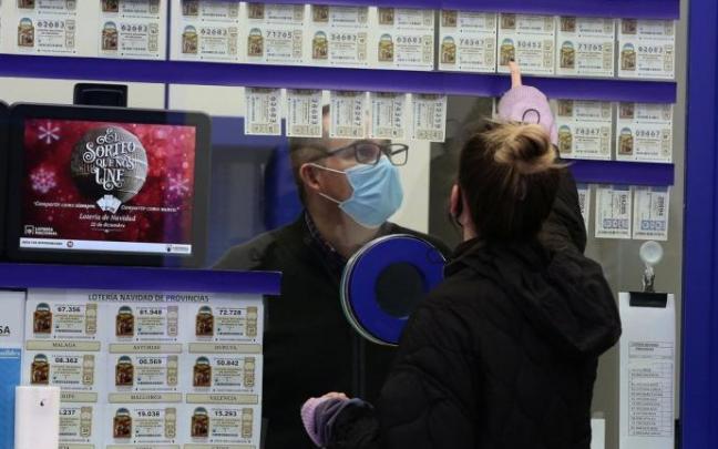 Una mujer elige un décimo en una administración de lotería. Una mujer elige un décimo en una administración de lotería.