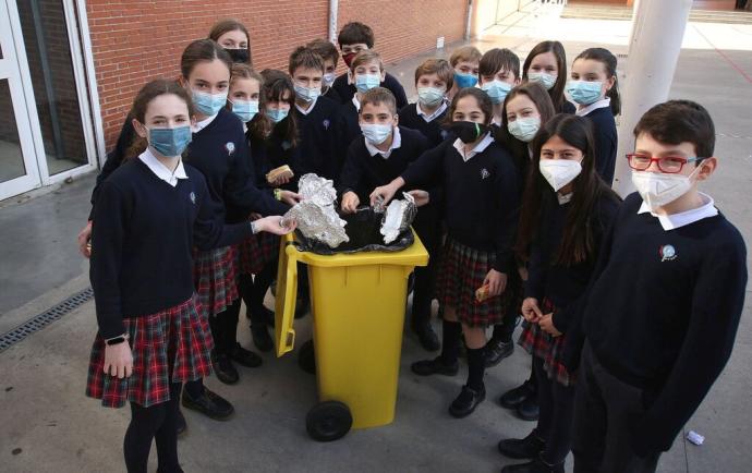 Un grupo de alumnos de 6º de Primaria, depositan el papel de aluminio en un contenedor del patio.