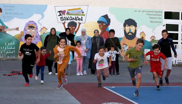 Niños a la carrera con sus madres detrás en el patio de Atakondoa.