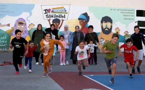 Niños a la carrera con sus madres detrás en el patio de Atakondoa.