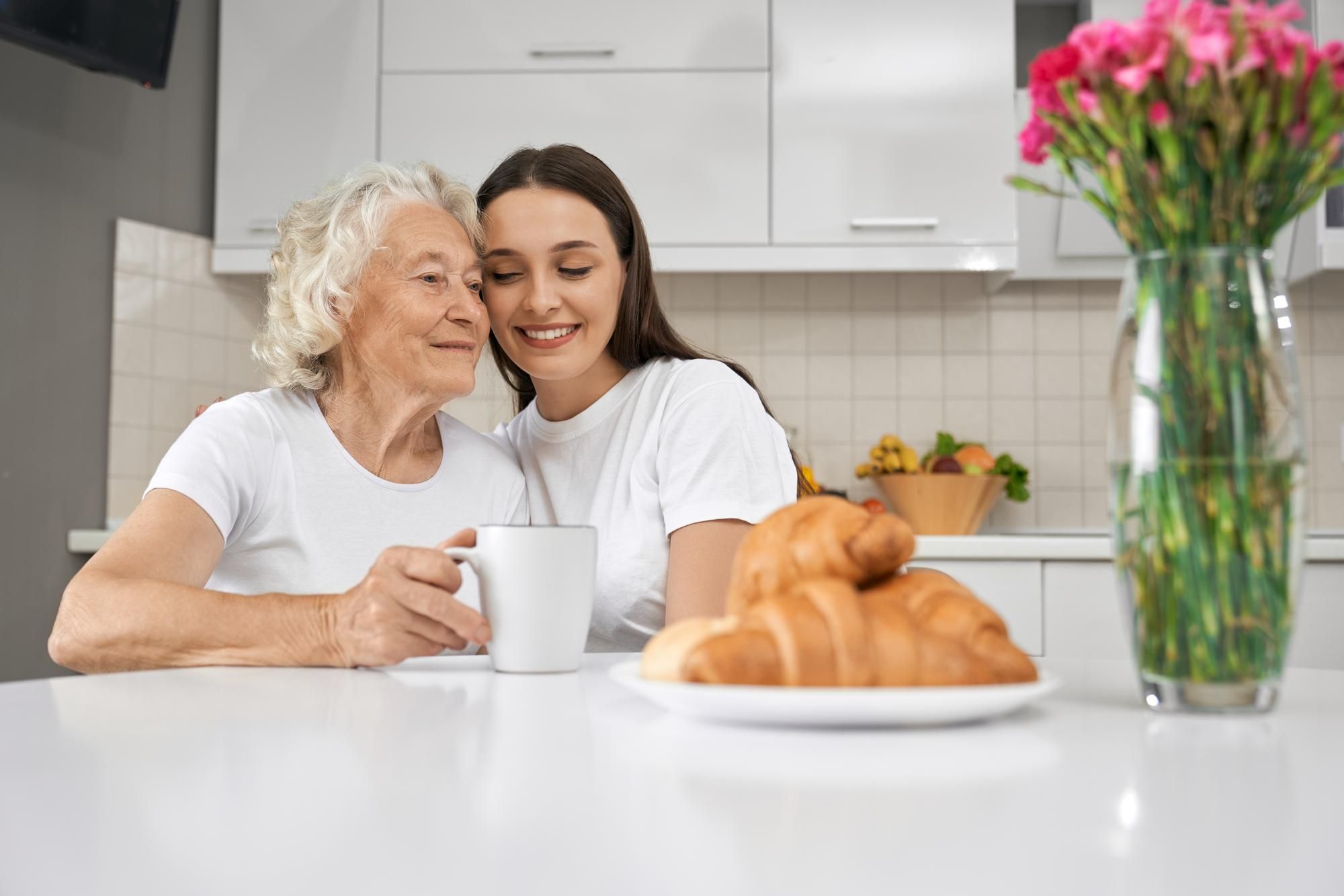 Una mujer joven acompaña a una anciana durante la merienda.