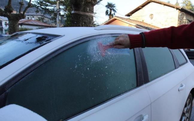 Una persona rasca el coche tras una helada