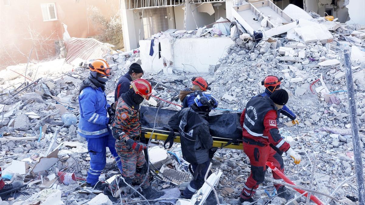 Miembros de los equipos de rescate trasladan el cadáver de una víctima de los terremotos.
