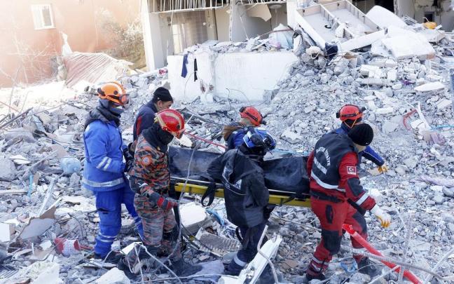 Miembros de los equipos de rescate trasladan el cadáver de una víctima de los terremotos.