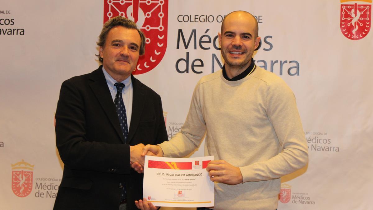 El presidente del Colegio de Médicos de Navarra, Rafael Teijeira, entrega el diploma de la Beca Seniro 2022 al cirujano maxilofacial Íñigo calvo.