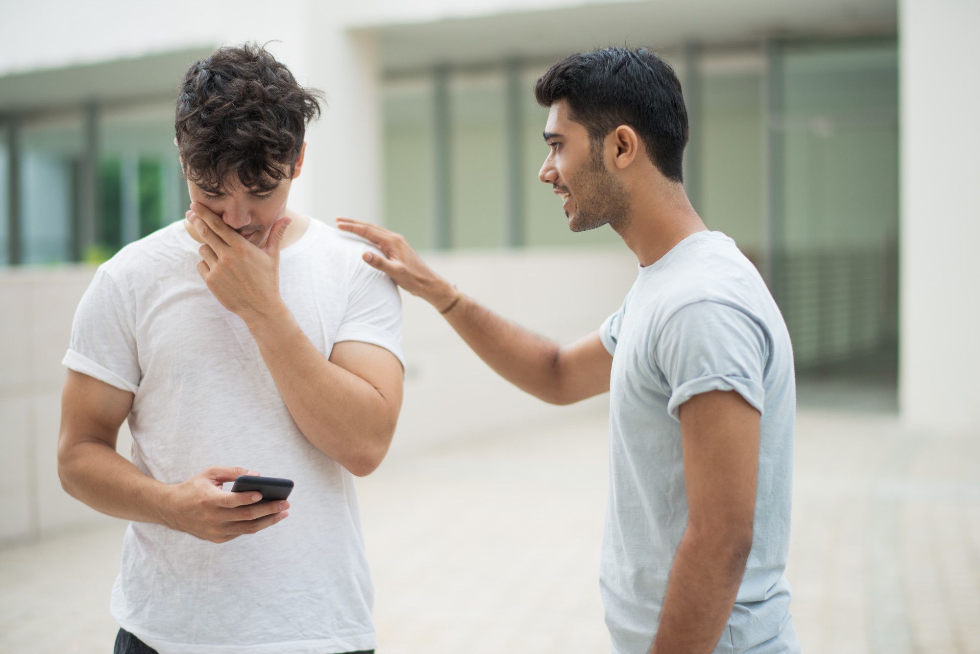 Un joven hace una confesión a su amigo mientras mira el móvil.