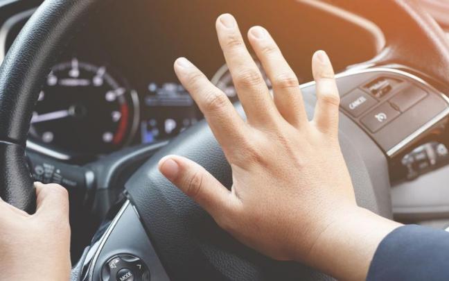 Un conductor presiona el claxon de su coche mientras conduce por una calle concurrida.