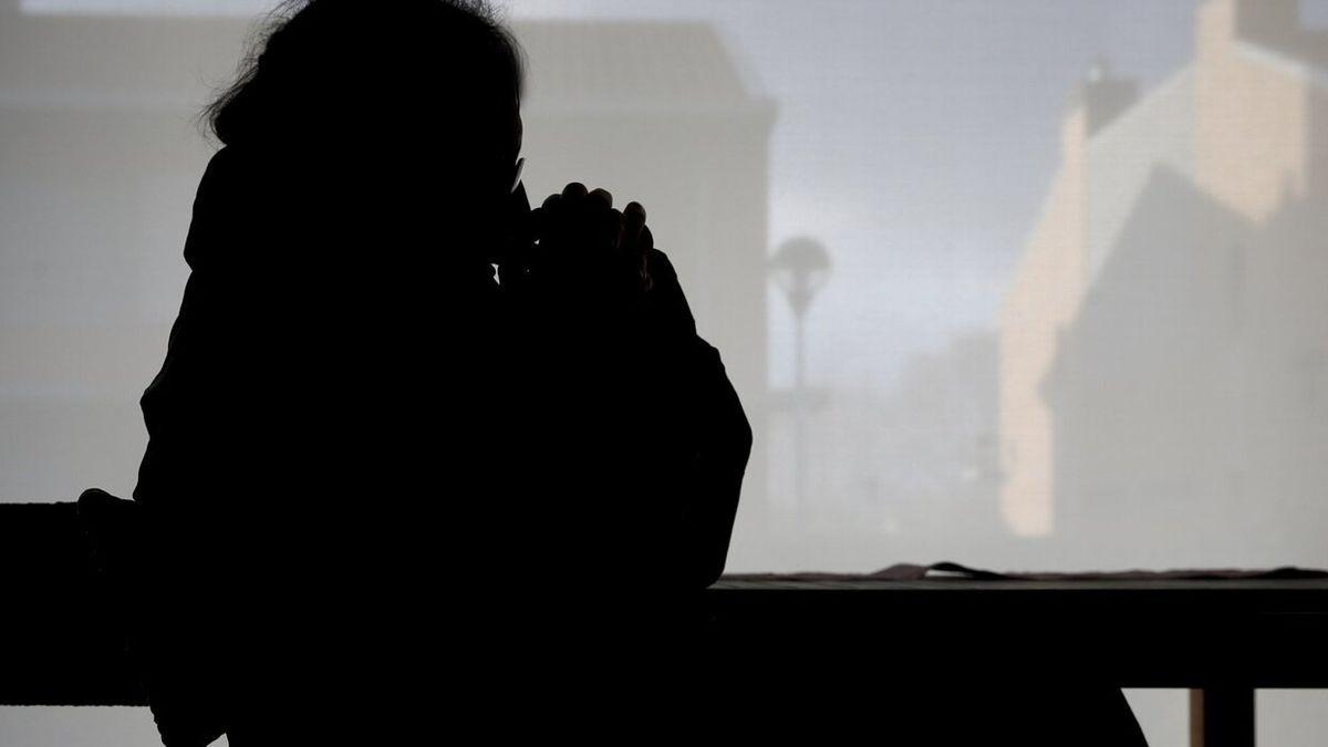 Una mujer se abriga en su casa con abrigos y mantas