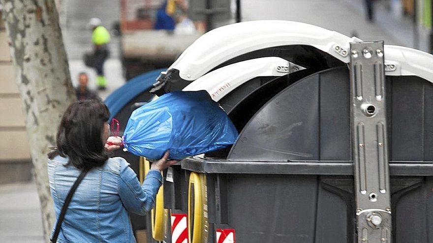 Una mujer, usando los contenedores de reciclaje.