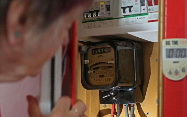 Una mujer londinense observa su contador de energía. Una mujer londinense observa su contador de energía.