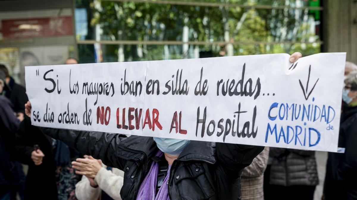 Una mujer sostiene una pancarta donde se lee "Si los mayores iban en silla de ruedas... se dio la orden de no llevar al hospital", durante una concentración en Madrid.