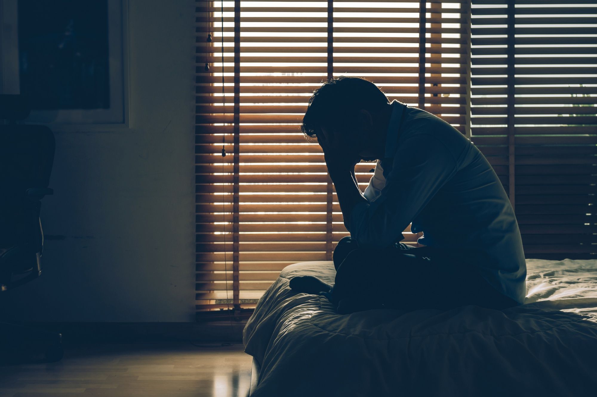 Un hombre deprimido sentado en la cama.