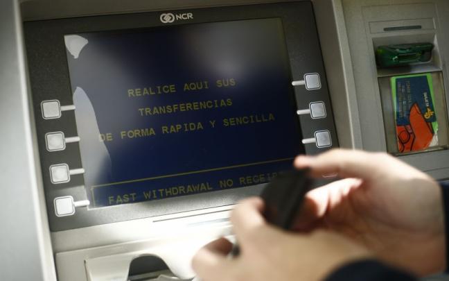 Un hombre saca dinero con la tarjeta de crédito en una sucursal bancaria.