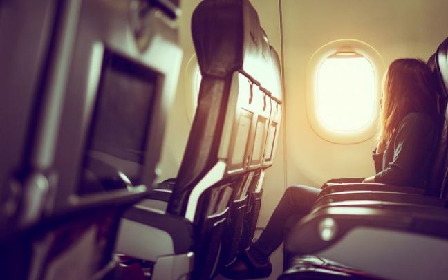 Una mujer mira por la ventanilla de un avión. Una mujer mira por la ventanilla de un avión.